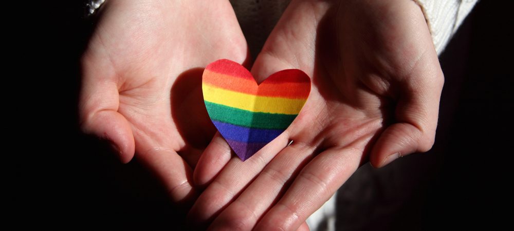 Zwei Hände mit einem Herz in Regenbogenfarben. Symbolbild für Toleranz und Solidarität. Für die Opfer des § 175 StGB soll nun in Darmstadt ein Mahnmal errichtet werden, das ebenso ein Zeichen für Toleranz sein soll. Über Entwürfe für das Mahnmal können die Bürger nun abstimmen.