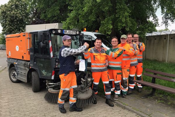 Mitarbeiter des Bauhofs der Stadt Heppenheim vor einer Kehrmaschine. Sie freuen sich über die Auszeichnung der Stadt Heppenheim als "Saubermacher-Stadt 2023".