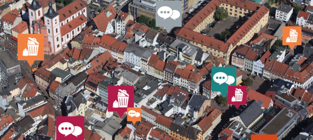 Foto der Stadt Fulda mit Blick von oben. Integriert sind die Icons vom Mängelmelder Fulda. Der digitale Bürgerservice ist zum 1.11.23 zunächst im Testbetrieb gestartet.