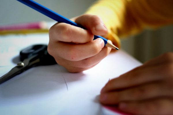 Kinderhand mit Bleistift am Schreibtisch; Symbolbild für Bildung und Artikelbild zur Umfrage vom Landkreis Lüneburg