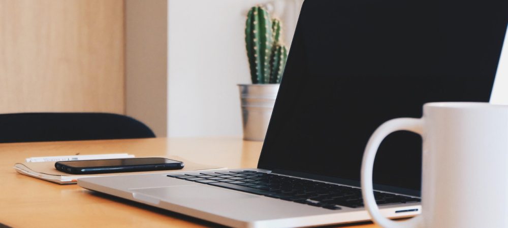 Schreibtisch mit Laptop, Kaffeetasse, Pflanzen. Vom Büro aus kann man ganz flexibel an einem der Online-Termine zur Bürgerbeteiligung teilnehmen