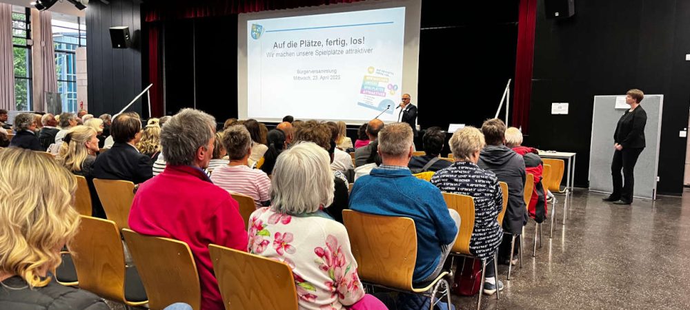 Teilnehmerinnen und Teilnehmer der Auftaktveranstaltung der Bürgerbeteiligung zum Spielplatz-Angebot in Usingen sitzen in Stuhlreihen und hören sich die Ideen und Vorschläge der Stadtverwaltung an.