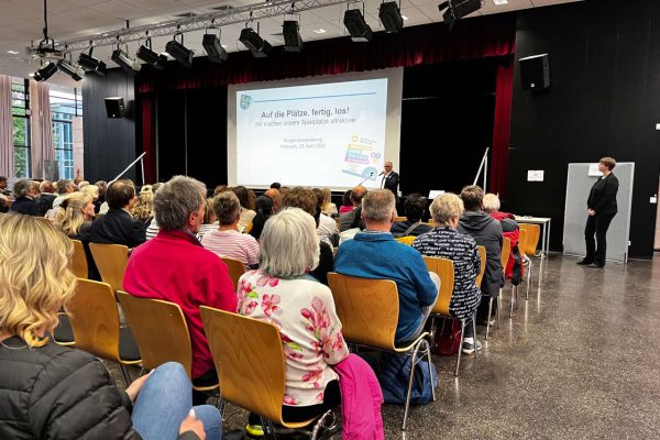 Teilnehmerinnen und Teilnehmer der Auftaktveranstaltung der Bürgerbeteiligung zum Spielplatz-Angebot in Usingen sitzen in Stuhlreihen und hören sich die Ideen und Vorschläge der Stadtverwaltung an.