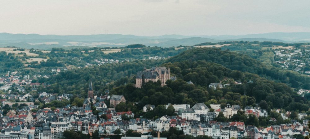 Luftbild von Marburg an der Lahn. Dort findet bis 6. Juli 2025 eine Online-Abstimmung statt, bei der sich die Bürger:innen zum Thema neue Ortsbeiräte in Marburg äußern können.