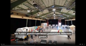 Screenshot vom Video-Rückblick zum Projekt "Griesheim. Innen Drin". Zu sehen: Große Halle mit Infoständen und vielen Besucherinnen und Besuchern